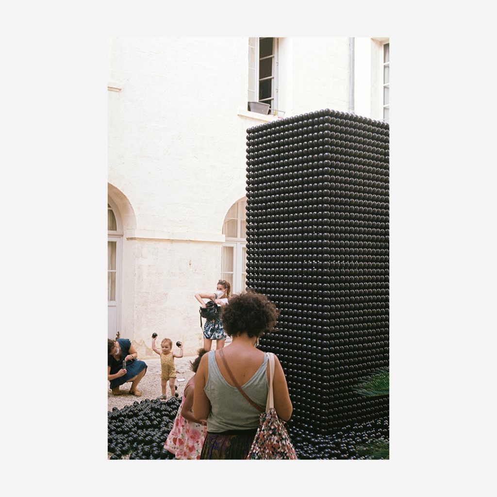 Visiteurs devant une œuvre d’art totem de base carrée constituée de sphères de plastique noir